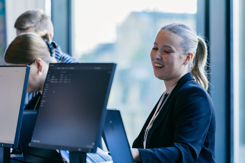 Hymyilevä nainen tietokoneen äärellä