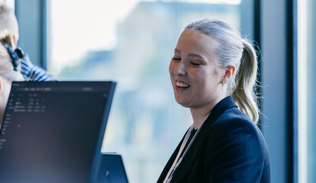 Hymyilevä nainen tietokoneen äärellä